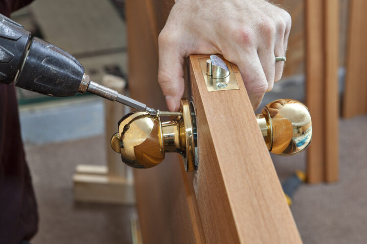 Worker Repairing A Deadbolt Lock Using A Drill